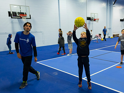child getting personalized coaching while shooting baskets