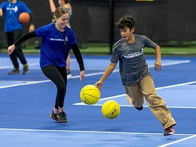 Kid practicing dribbling with their basketball coach