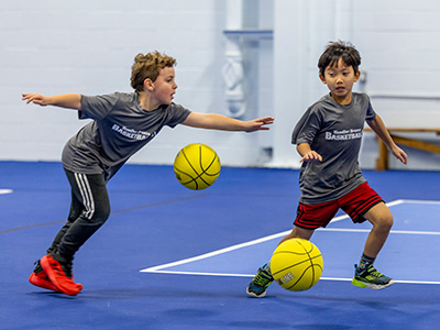 2 kids running with basketballs doing a drill.