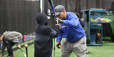 kid recieving specialized training from a coach to work on his batting skills