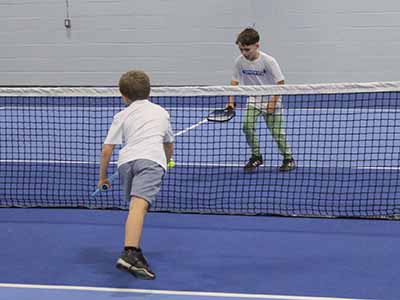 Young boys learn to play pickleball on the court