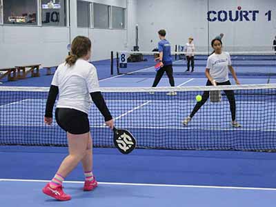 girls dink across the net at the indoor courts